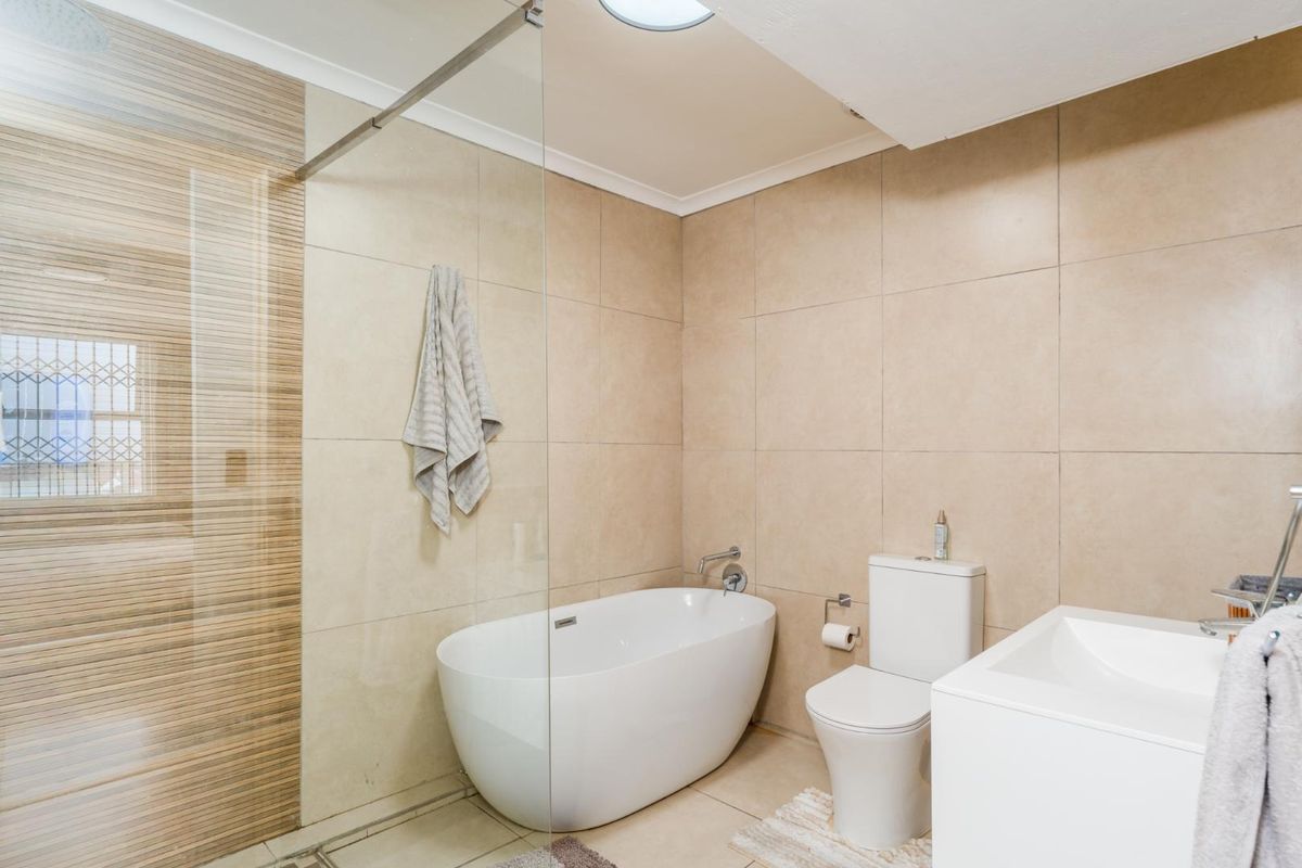 Modern bathroom featuring a freestanding bathtub, glass shower screen, wall-mounted toilet, and contemporary tiled finishes.