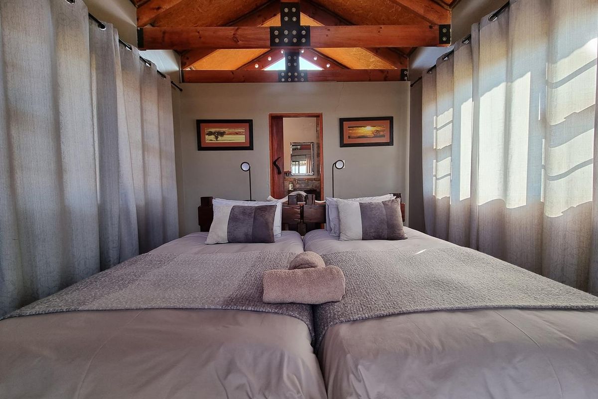 A cozy bedroom featuring exposed timber roof trusses, high ceilings, and an en-suite bathroom entrance, creating a warm and inviting atmosphere.