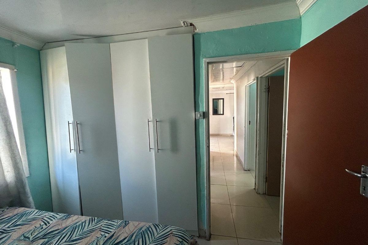 Bedroom featuring built-in white cabinetry and tiled flooring, with a doorway leading into a tiled hallway.