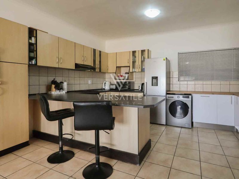 A functional kitchen featuring laminate cabinetry, a tiled backsplash, built-in cooking appliances, and a breakfast bar with tiled flooring throughout.