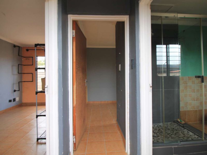 A central hallway providing access to adjacent rooms, featuring tiled flooring and a view into a bathroom with a glass-enclosed shower.