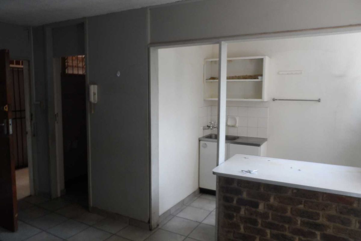 A dated kitchen area featuring a brick breakfast bar, tiled flooring, and basic built-in cabinetry, offering potential for a modern renovation.
