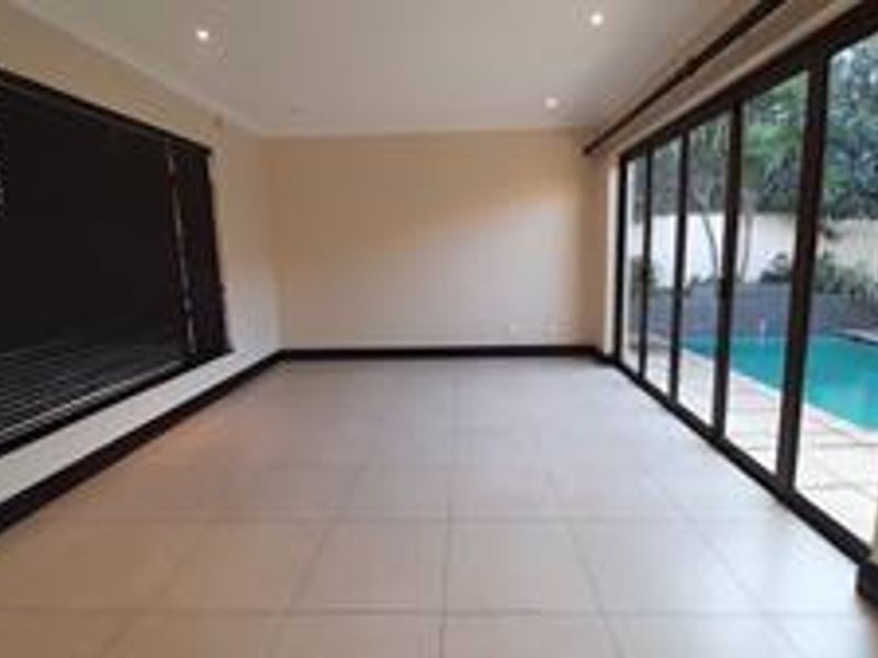 Spacious, light-filled living area featuring large aluminium sliding doors that open directly onto the pool area, finished with neutral tiles and recessed lighting.