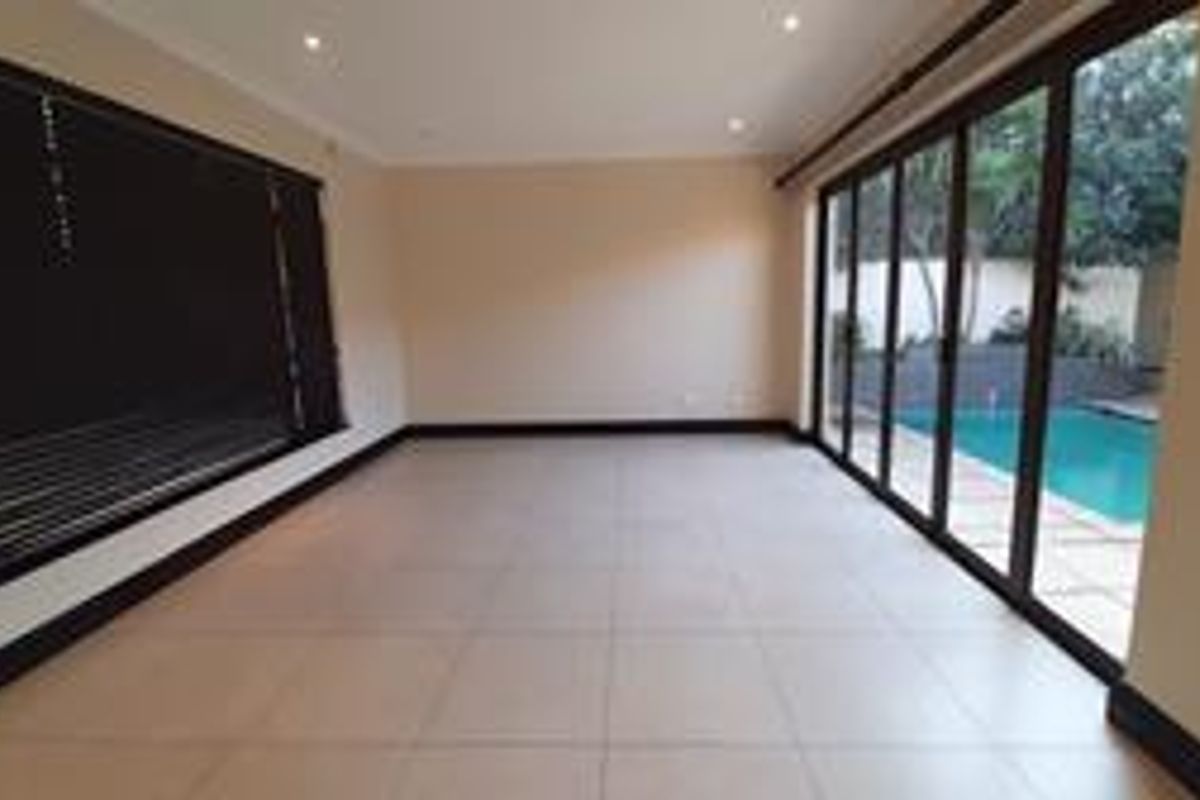 Spacious, light-filled living area featuring large aluminium sliding doors that open directly onto the pool area, finished with neutral tiles and recessed lighting.