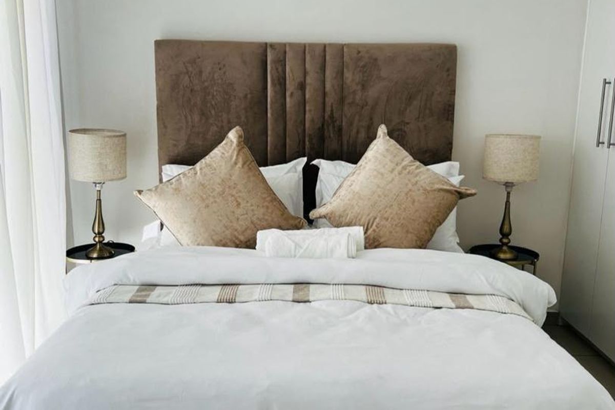 A well-maintained bedroom featuring neutral tones, tiled flooring, and a built-in wardrobe, offering a clean and comfortable living space.
