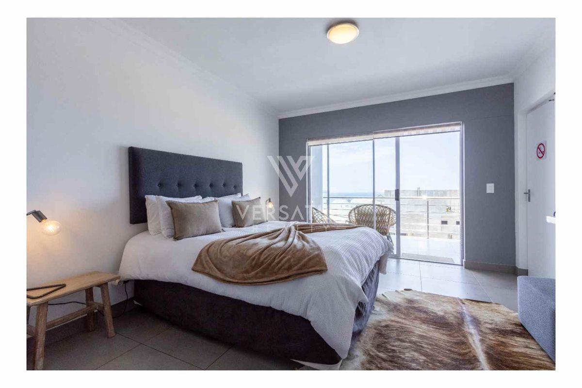 Spacious bedroom featuring large sliding glass doors that open onto a private balcony with ocean views.