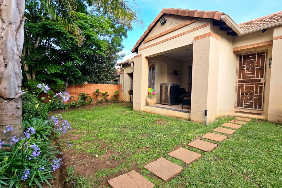 A private rear garden featuring a covered patio, paved walkway, and established landscaping, providing a pleasant outdoor space for the townhouse.