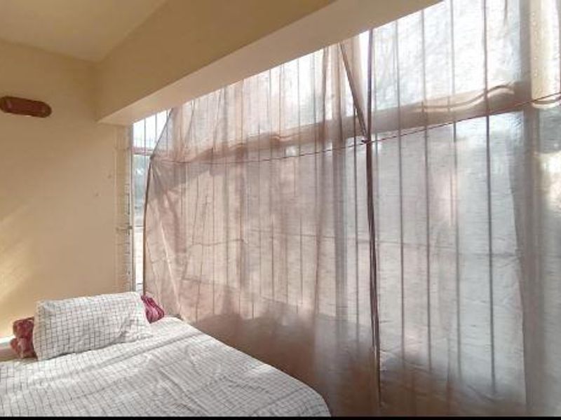A bedroom featuring a large window with security bars, allowing natural light into the space.