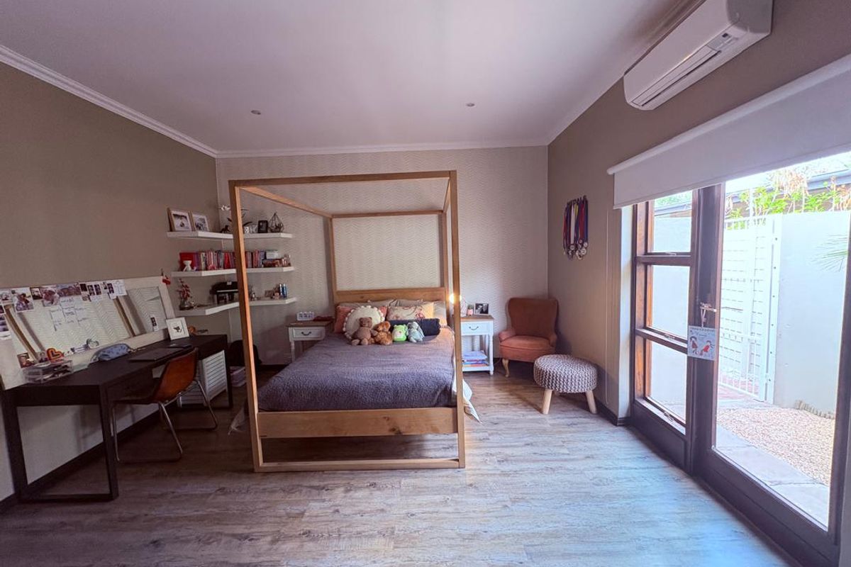 Spacious bedroom featuring timber-look flooring, recessed lighting, a split-system air conditioner, and direct access to an outdoor area through sliding glass doors.