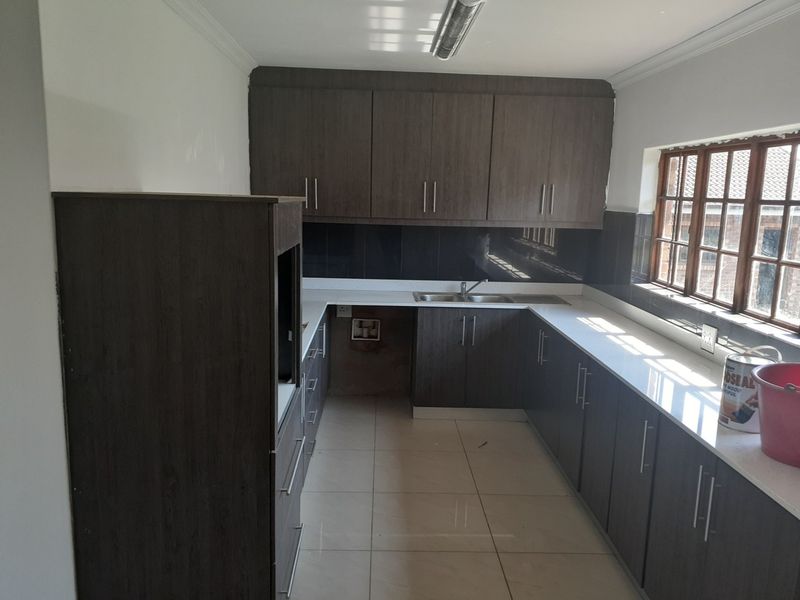 A functional kitchen featuring dark wood-look cabinetry, white countertops, tiled flooring, and a dedicated space for a built-in oven.