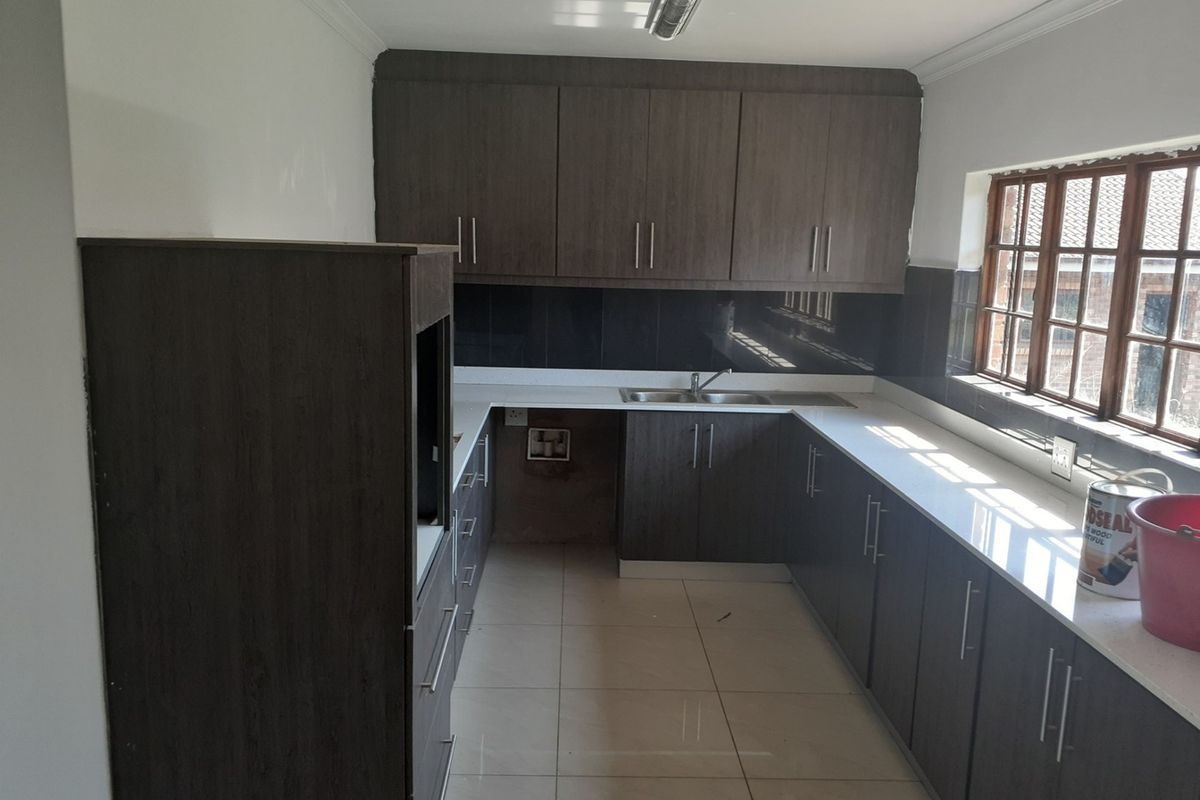 A functional kitchen featuring dark wood-look cabinetry, white countertops, tiled flooring, and a dedicated space for a built-in oven.