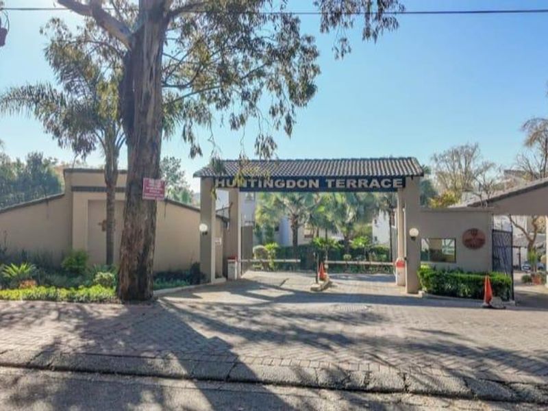 The entrance to Huntingdon Terrace featuring a secure gated access point with a paved driveway and perimeter boundary walls.