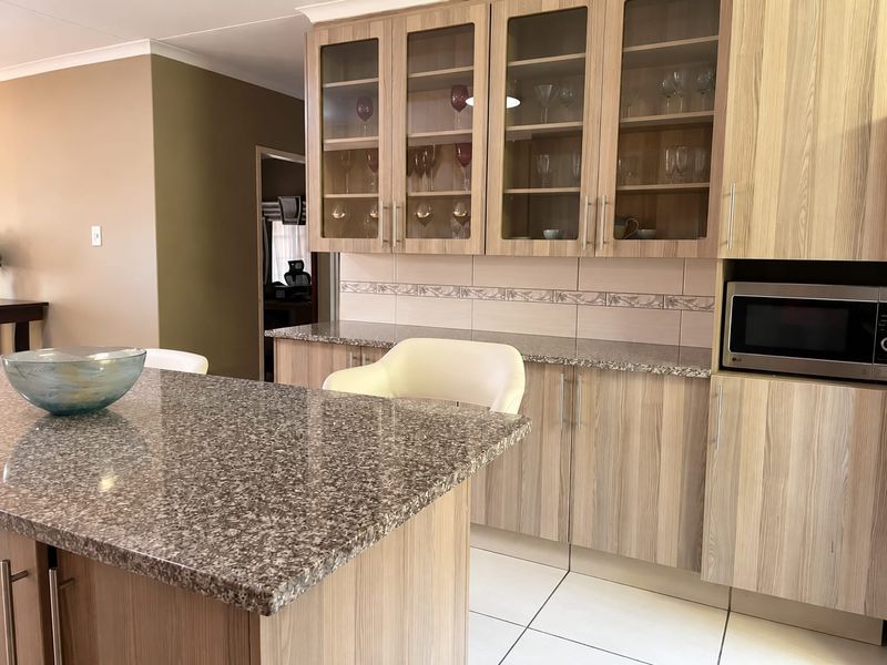 A well-maintained kitchen featuring wood-finish cabinetry, granite countertops, a tiled backsplash, and a built-in microwave, offering a functional and clean workspace.