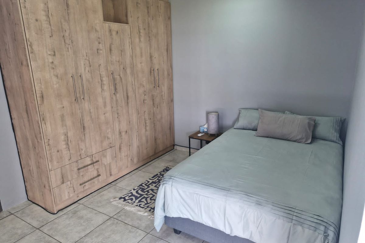 A well-maintained bedroom featuring large, built-in wooden wardrobes and neutral tiled flooring.