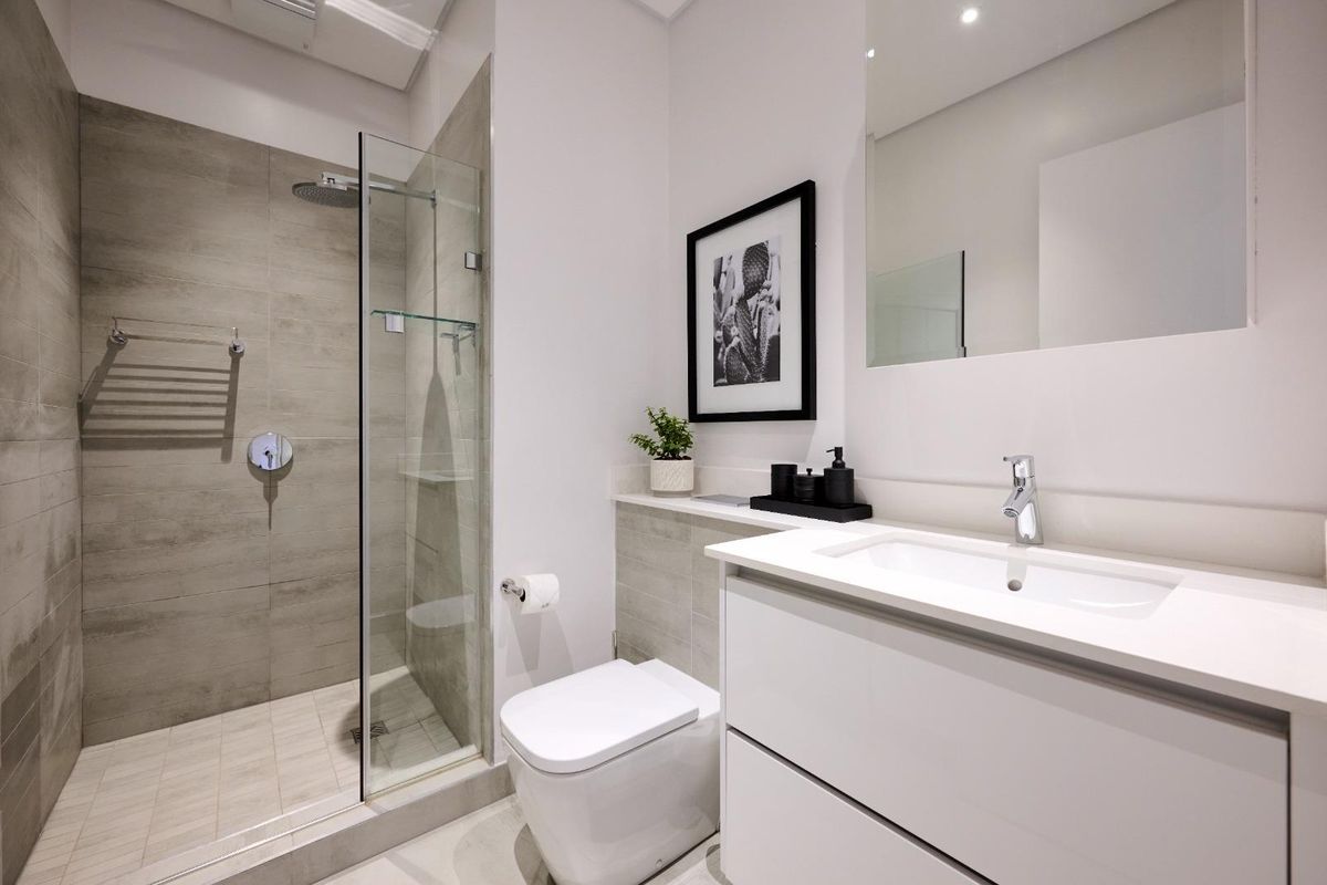 Modern bathroom featuring a glass-enclosed walk-in shower, wall-mounted toilet, and a sleek vanity with integrated basin and mirror.