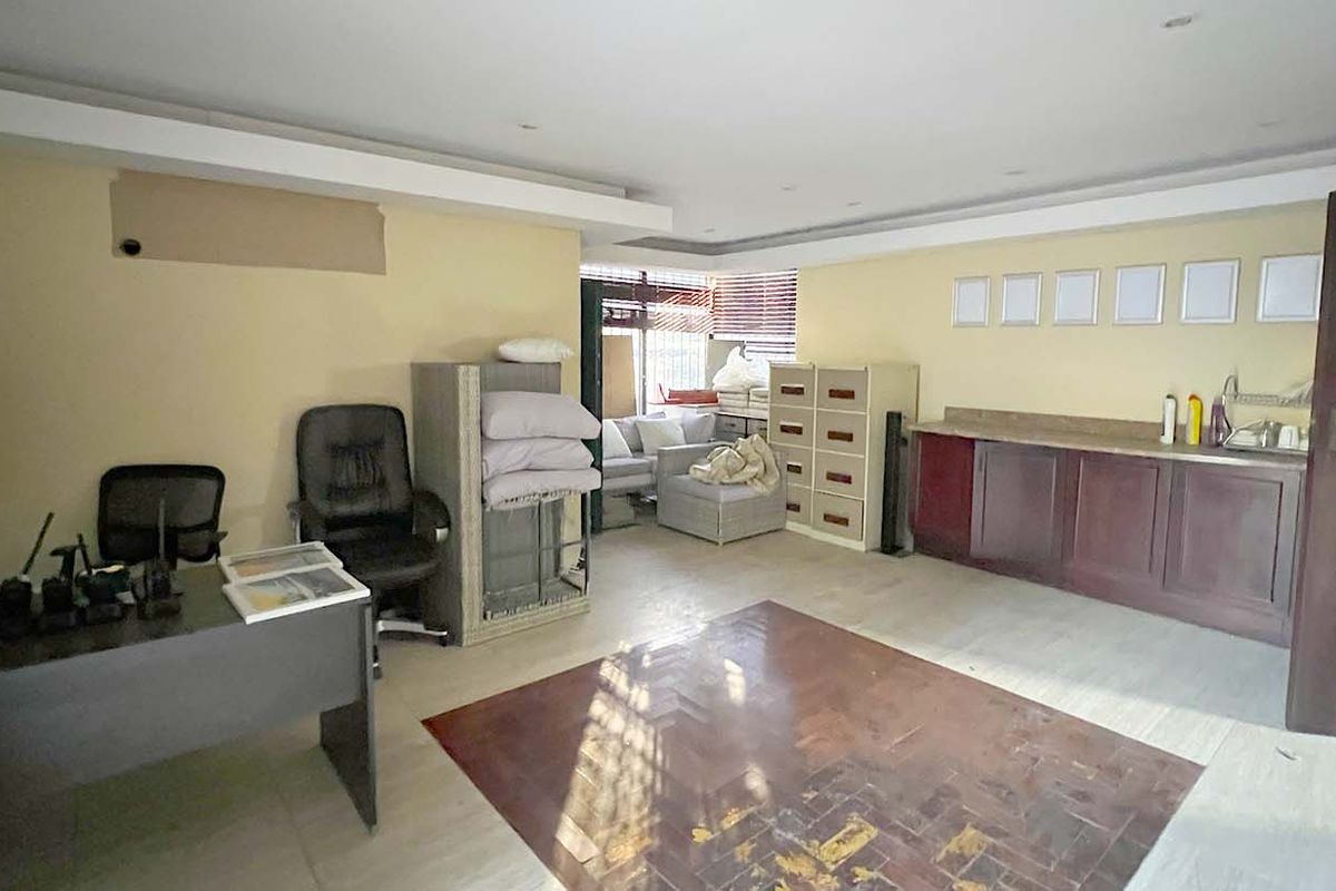 Spacious office area featuring a built-in kitchenette, recessed lighting, and parquet flooring, offering a functional workspace layout.