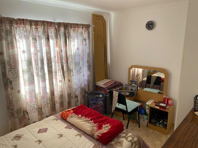 A functional bedroom featuring tiled flooring and a window with curtain fittings, offering a neutral space ready for personalization.