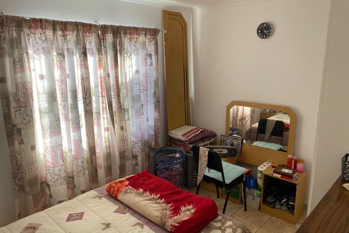 A functional bedroom featuring tiled flooring and a window with curtain fittings, offering a neutral space ready for personalization.