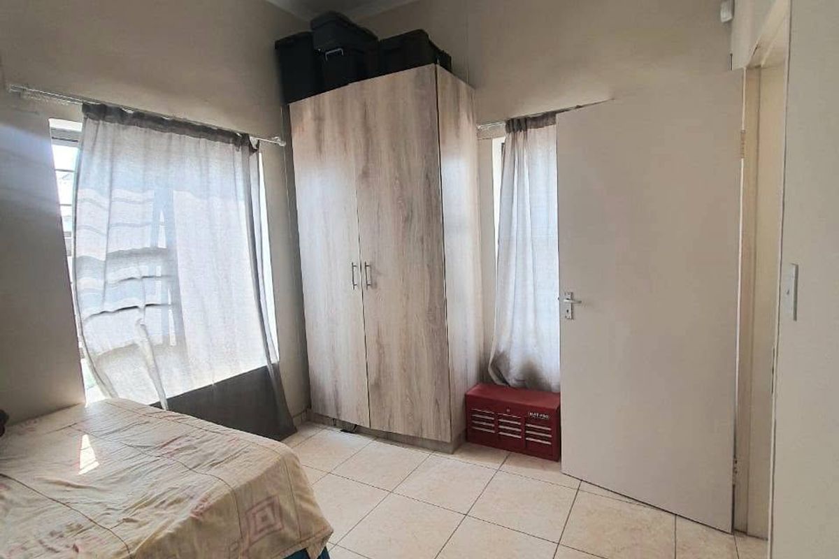 A functional bedroom featuring neutral tiled flooring and a built-in wardrobe, offering a clean and practical living space.