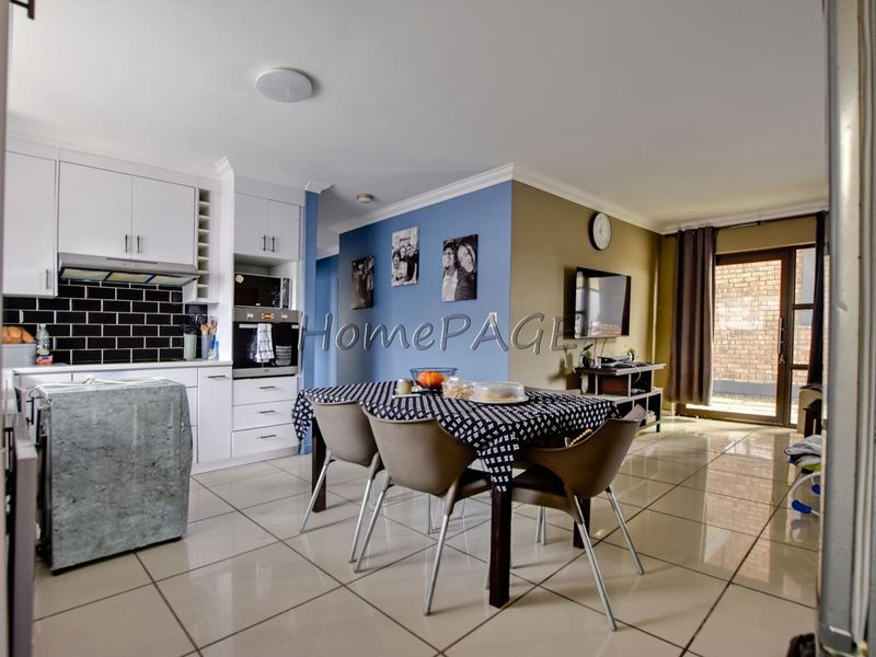 Open-plan living and dining area featuring a modern kitchen with white cabinetry, subway tile backsplash, and tiled flooring leading to an outdoor space.