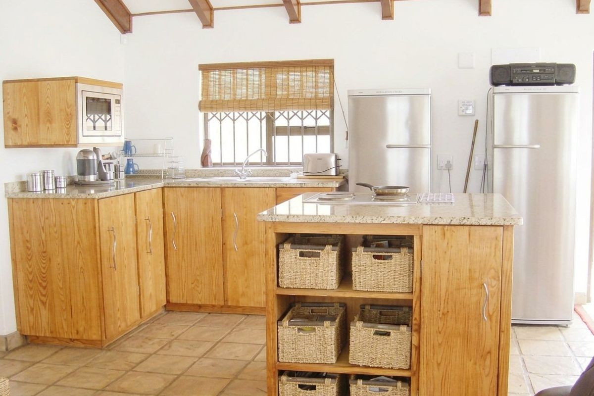 A functional kitchen featuring wooden cabinetry, granite countertops, a central island, and exposed timber ceiling beams, providing a warm and practical cooking space.