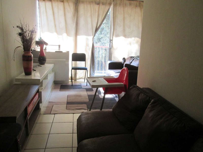 A living room area featuring tiled flooring and a sliding glass door leading to an outdoor space.