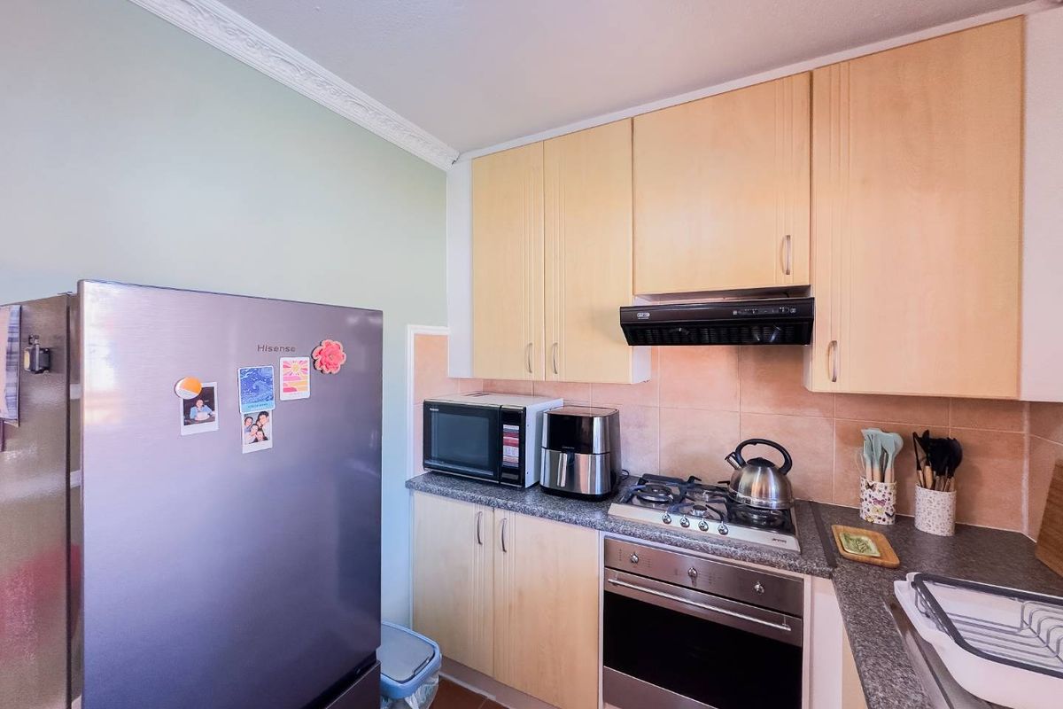 A functional kitchen featuring light wood-finish cabinetry, granite countertops, a gas hob, and a built-in oven with a tiled backsplash.
