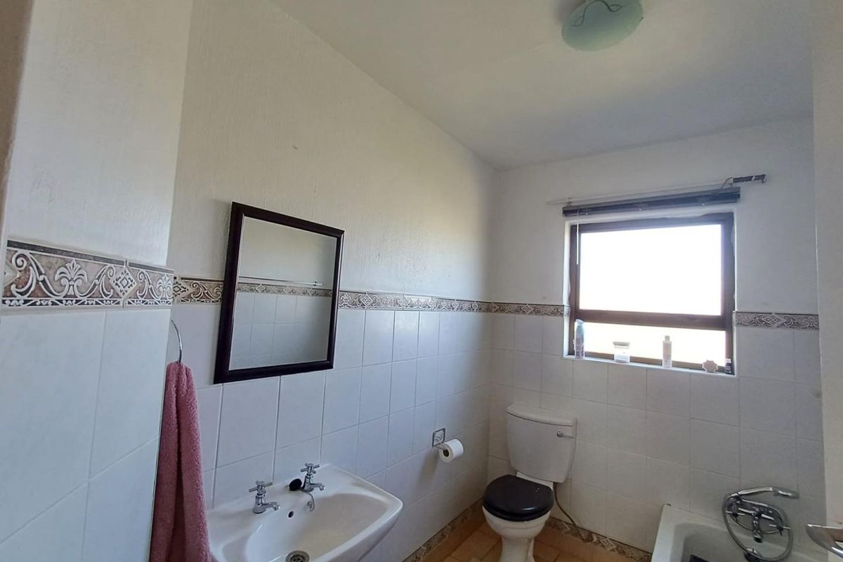A functional bathroom featuring a pedestal washbasin, toilet, and bathtub with ceramic wall and floor tiling.