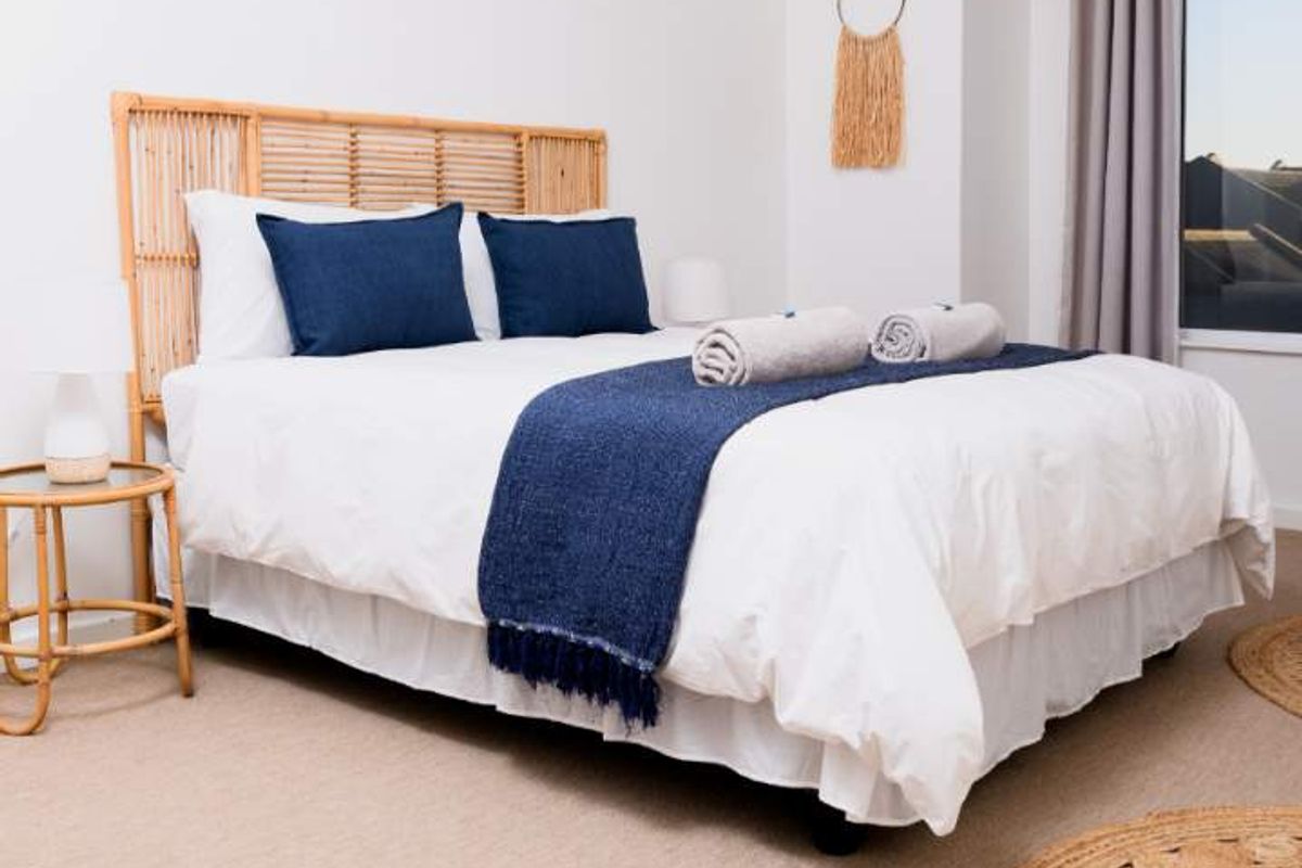 A bright and well-maintained bedroom featuring neutral carpeting, clean white walls, and a large window allowing for natural light.