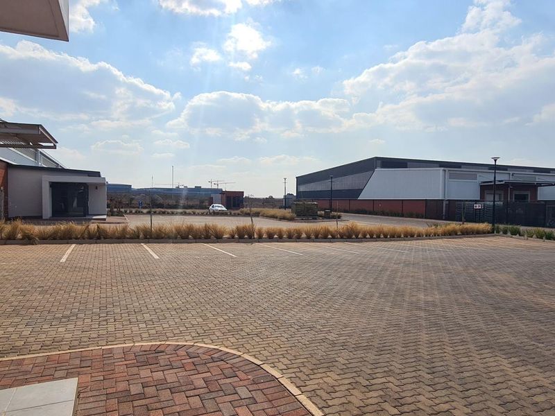 Spacious paved parking area serving an industrial complex with brick and metal clad warehouse structures.