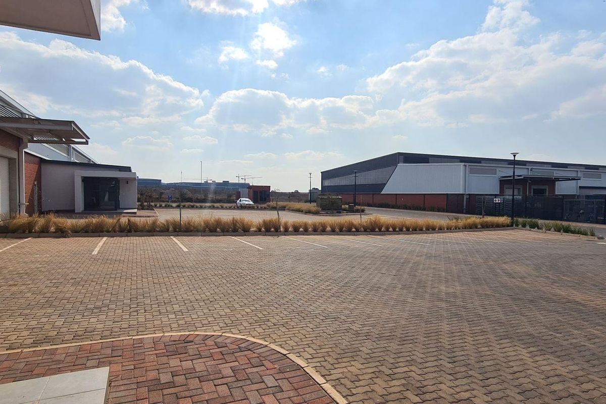 Spacious paved parking area serving an industrial complex with brick and metal clad warehouse structures.