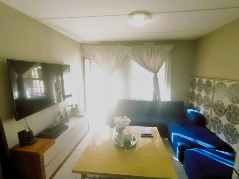 A living room featuring tiled flooring and a central ceiling light fixture, with natural light entering from the window area.