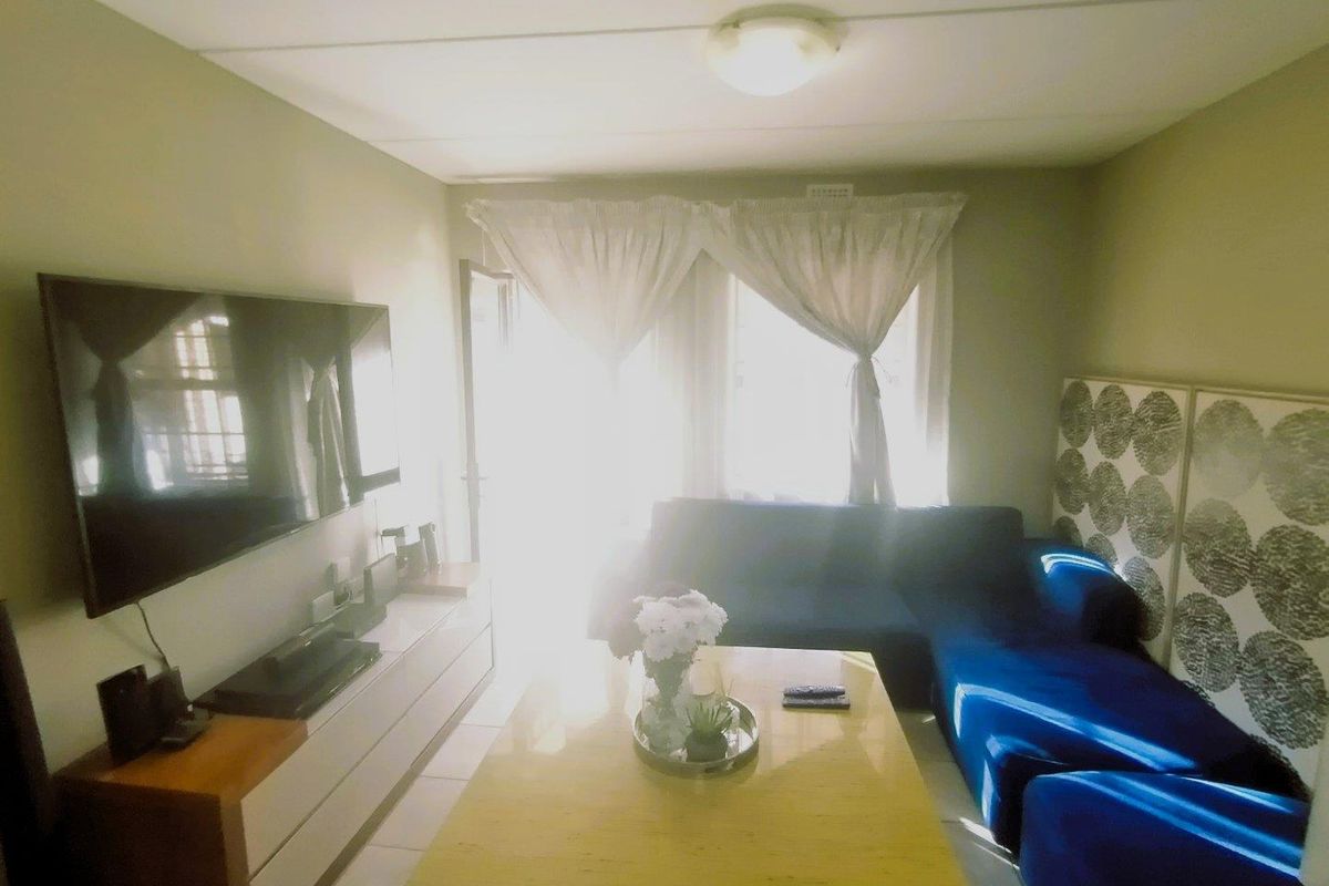 A living room featuring tiled flooring and a central ceiling light fixture, with natural light entering from the window area.
