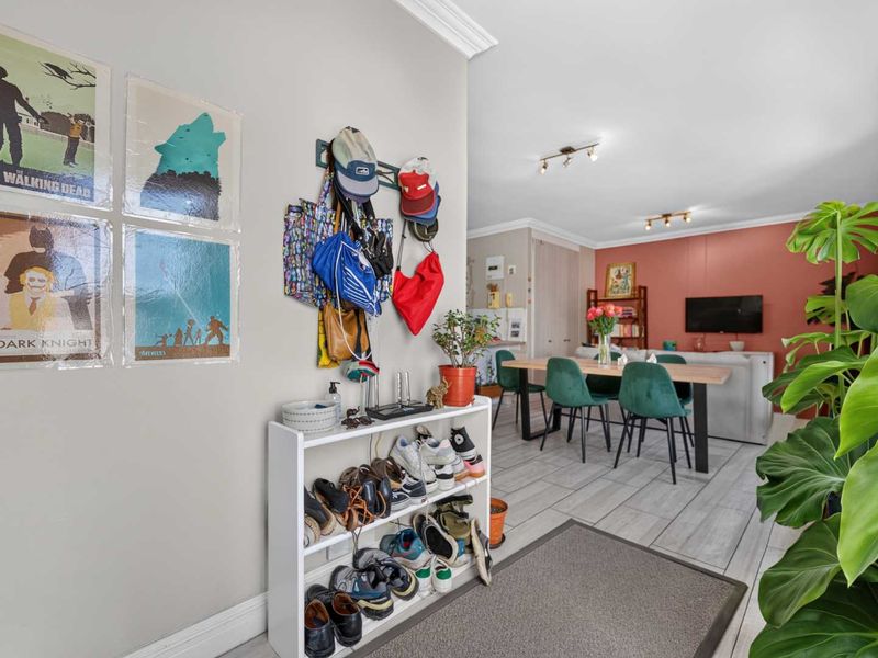An open-plan living and dining area featuring light-toned tiled flooring, neutral wall finishes, and recessed ceiling lighting, creating a bright and functional living space.