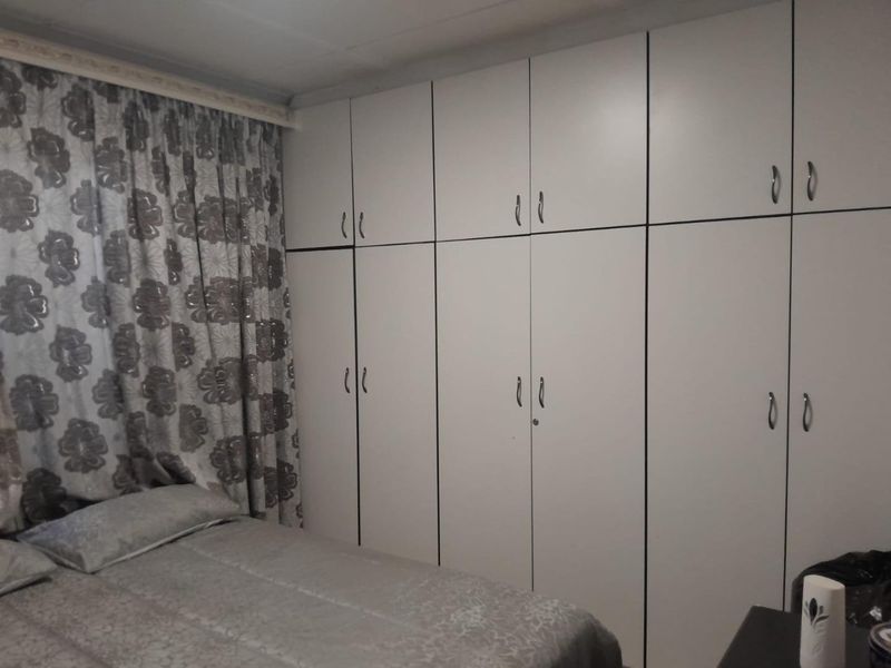 A bedroom featuring extensive floor-to-ceiling built-in cupboards providing ample storage space.