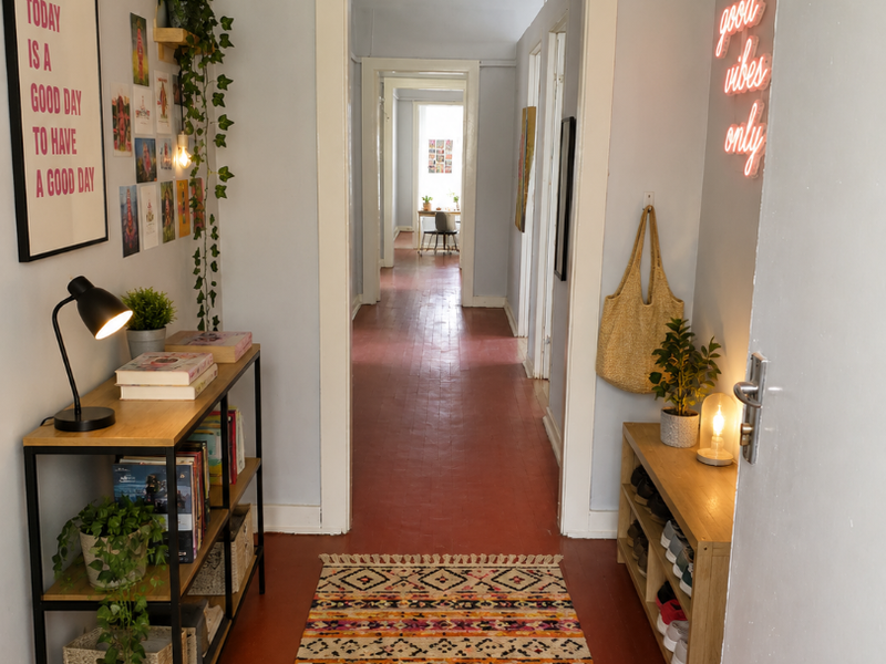 A bright, welcoming hallway featuring painted wooden floors and a series of connecting doorways leading through the apartment.