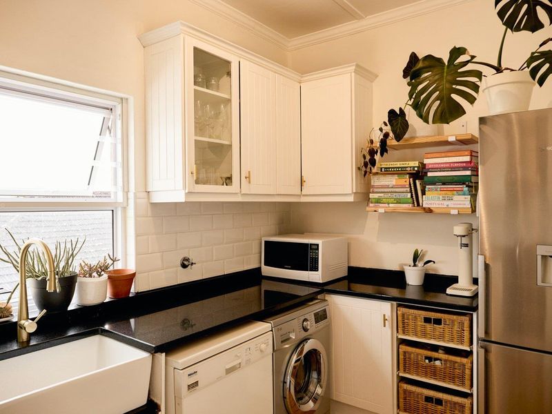 A well-appointed kitchen featuring white shaker cabinetry, black granite countertops, subway tile backsplash, and an apron front sink with brass fixtures.