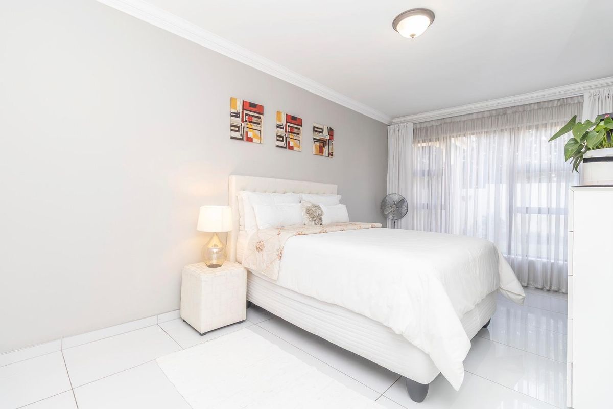 A bright and well-maintained bedroom featuring neutral wall tones, polished tiled flooring, and elegant ceiling cornicing, offering a clean and comfortable living space.