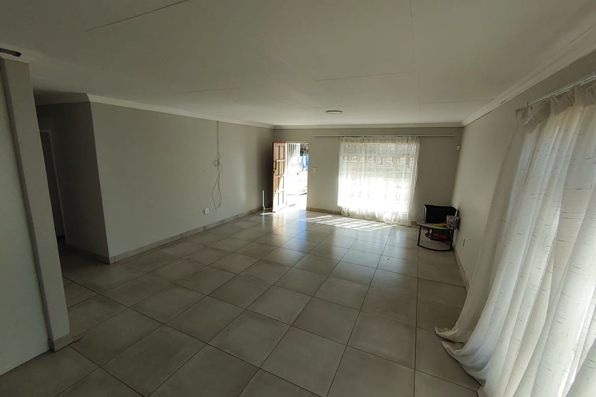 A spacious, empty living area featuring neutral tiled flooring and natural light, providing a blank canvas for interior design and personalization.