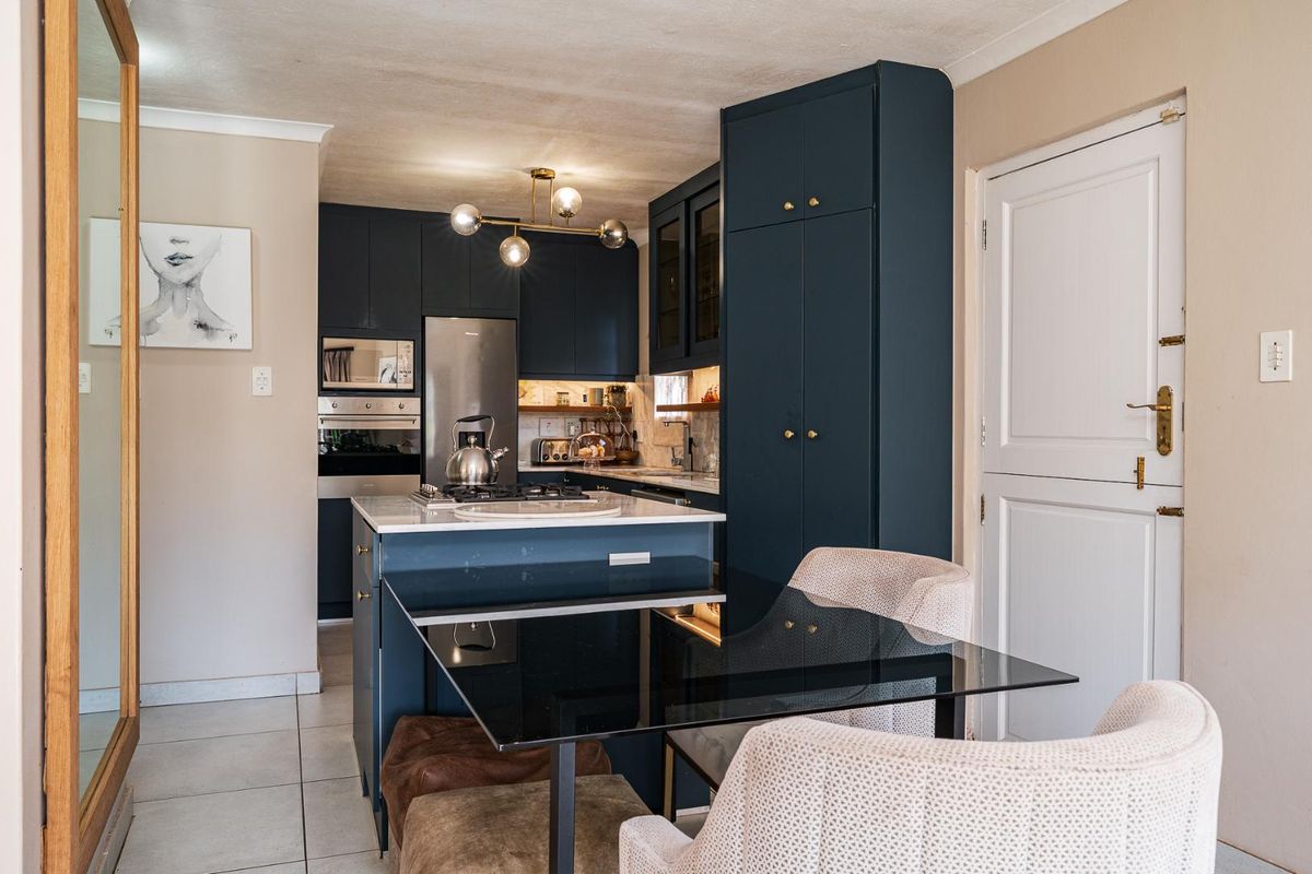 Modern kitchen featuring dark blue cabinetry, stone countertops, a central island with a built-in gas hob, and integrated oven and microwave.