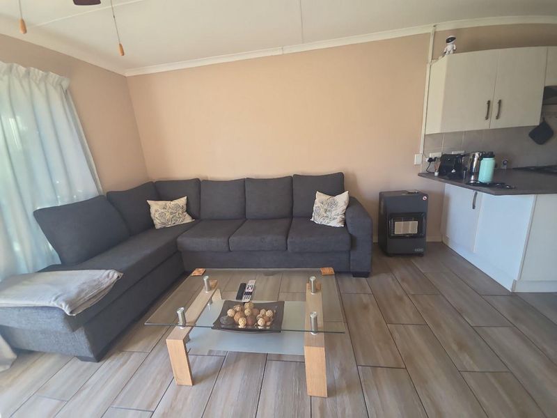 Open plan living area featuring tiled flooring and a compact kitchen with built-in cabinetry and laminate countertops.