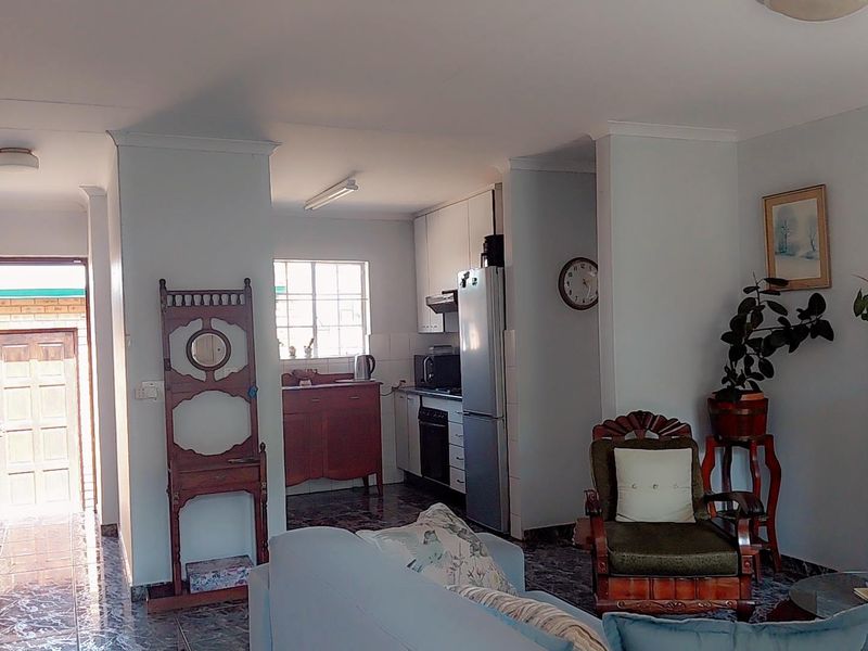 Open-plan living area featuring tiled flooring and a functional kitchen with built-in cabinetry, oven, and extractor fan, leading to an exterior entrance.
