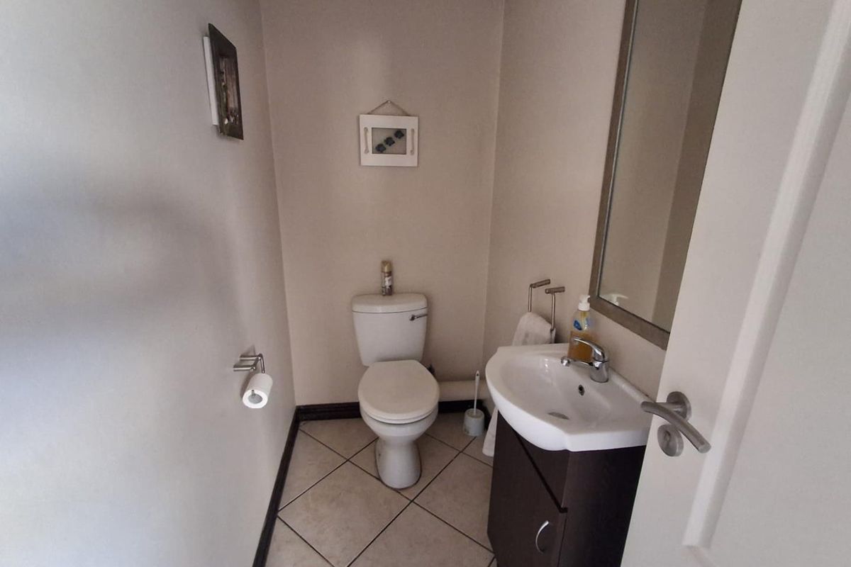 A compact guest cloakroom featuring a wall-mounted vanity basin, a standard toilet, and tiled flooring.