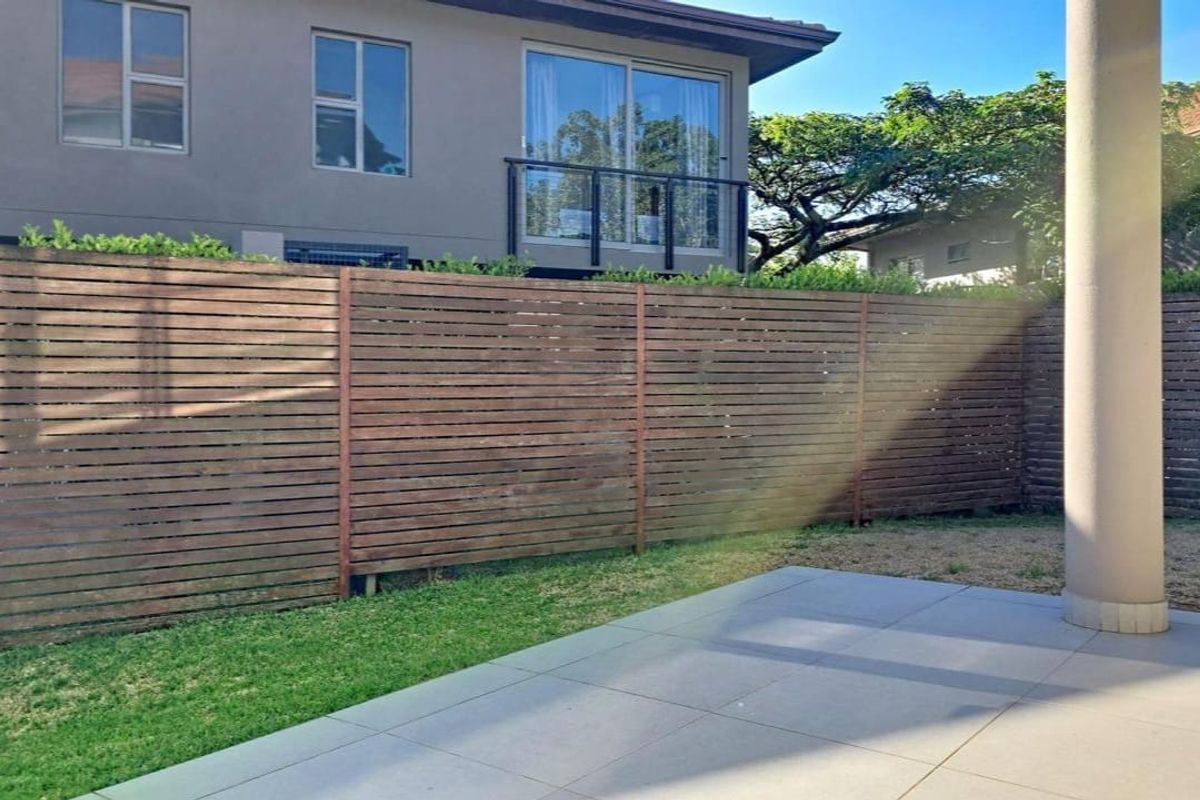 A private rear garden area featuring a tiled patio, timber slat fencing, and a view of the townhouse exterior with sliding door access.