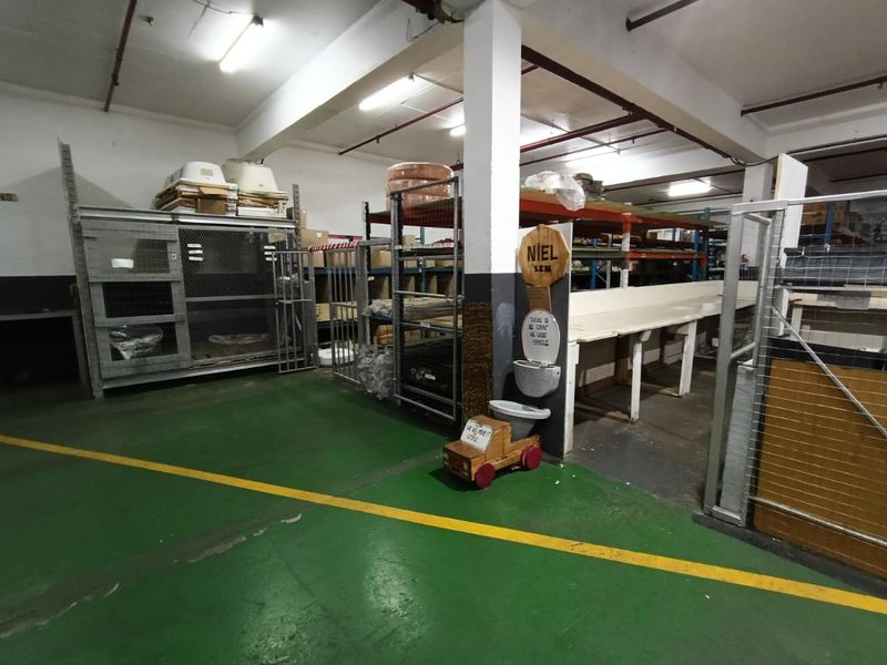 Industrial utility space featuring concrete flooring, exposed ceiling infrastructure, and heavy-duty storage shelving units suitable for warehouse or workshop operations.