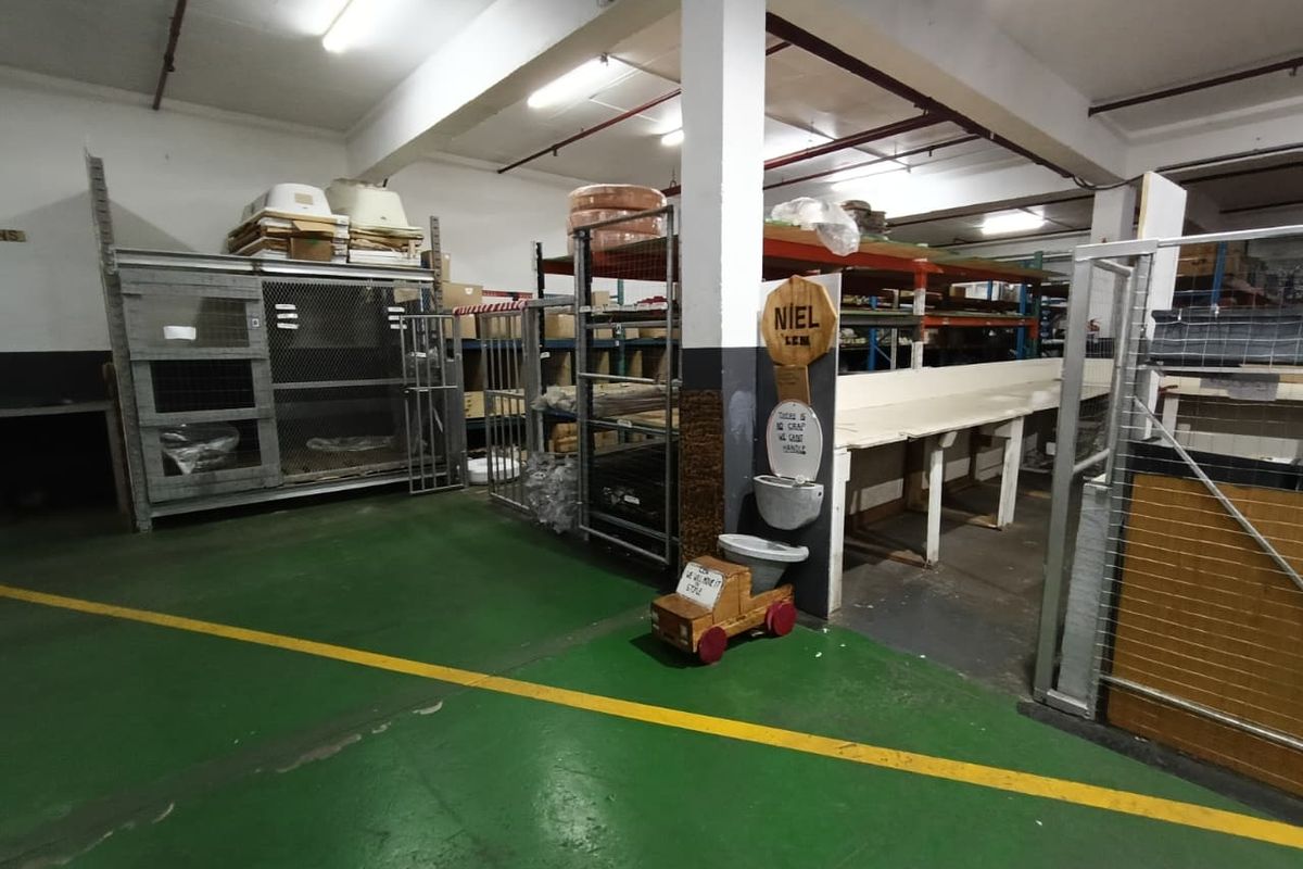 Industrial utility space featuring concrete flooring, exposed ceiling infrastructure, and heavy-duty storage shelving units suitable for warehouse or workshop operations.