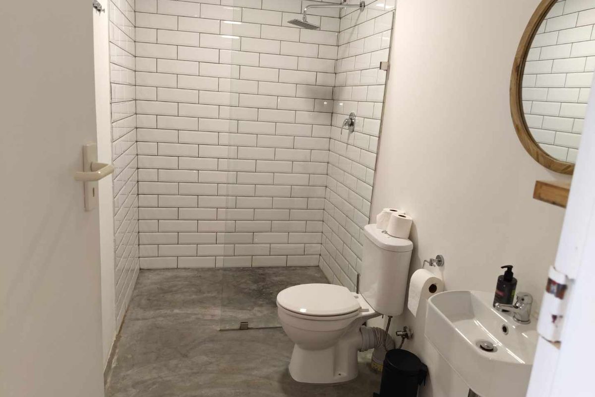 Modern bathroom featuring a walk-in shower with white subway tiles, a rainfall showerhead, a wall-mounted basin, and a toilet.