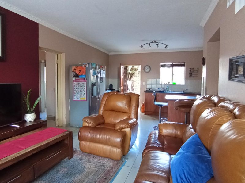 Open plan living area featuring a kitchen with breakfast bar, tiled flooring, and coving, seamlessly connecting to the lounge space.