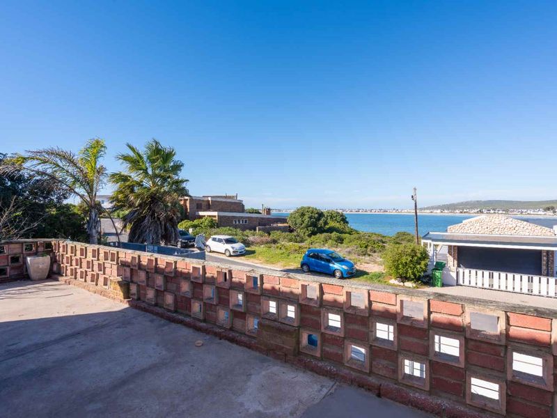 Elevated view of the coastline and surrounding neighbourhood, featuring a concrete patio area enclosed by a decorative breeze block wall.
