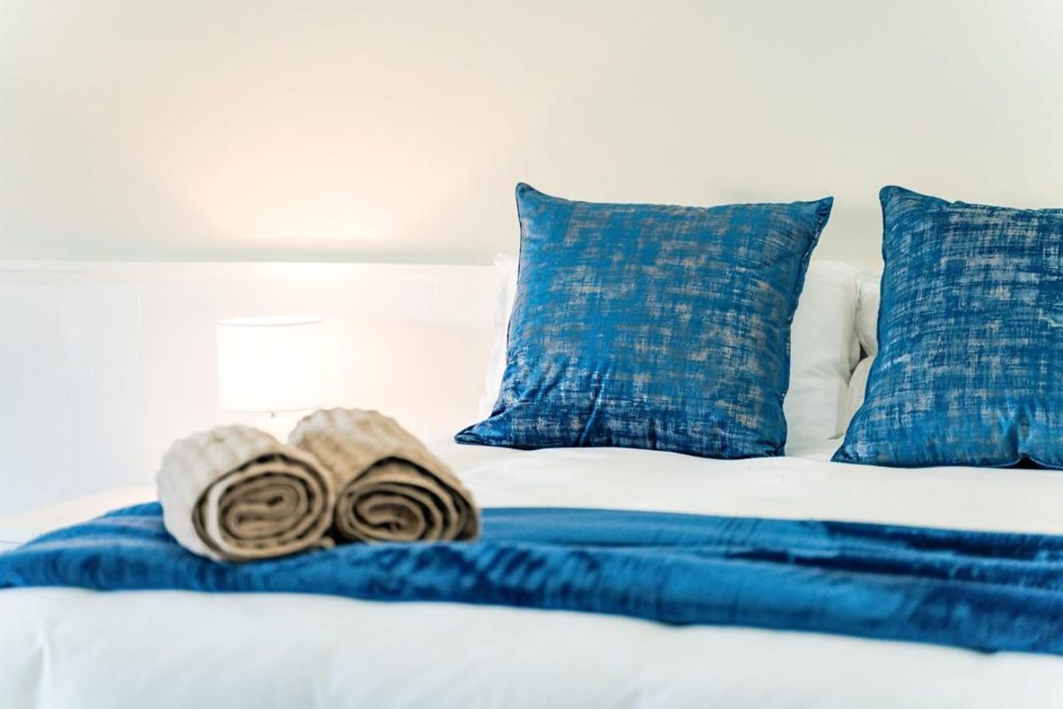 A close-up view of a bedroom setup featuring a clean, neutral wall backdrop and a comfortable bed arrangement.